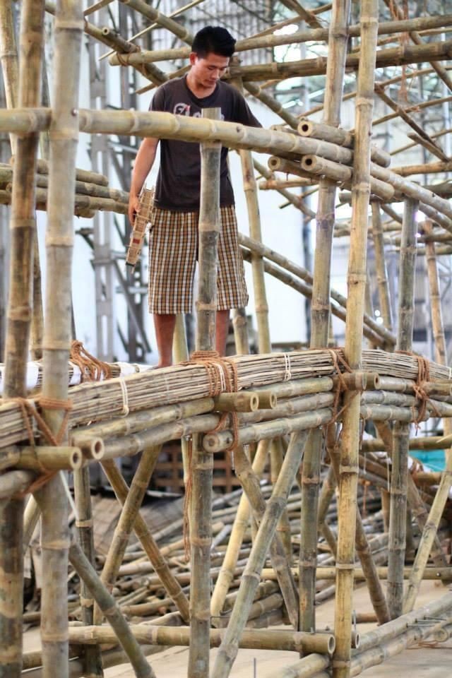 A bamboo artisan works on structural beams at a sustainable construction project.